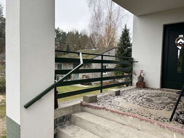 Ciemna poręcz stalowa przy zewnętrznym podeście wejściowym