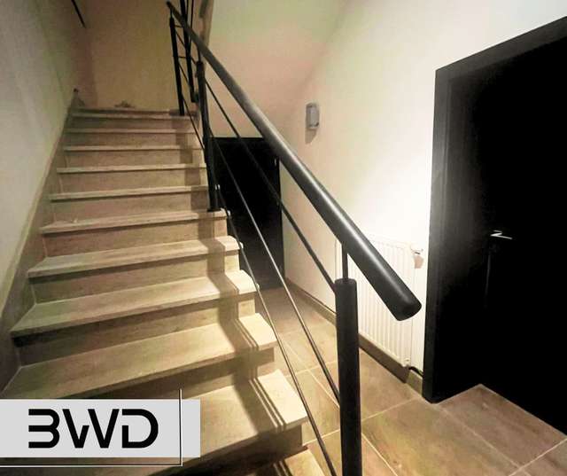 Czarna stalowa balustrada przy jasnych schodach wewnętrznych