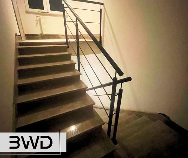 Czarna metalowa balustrada z poręczą przy kamiennych schodach