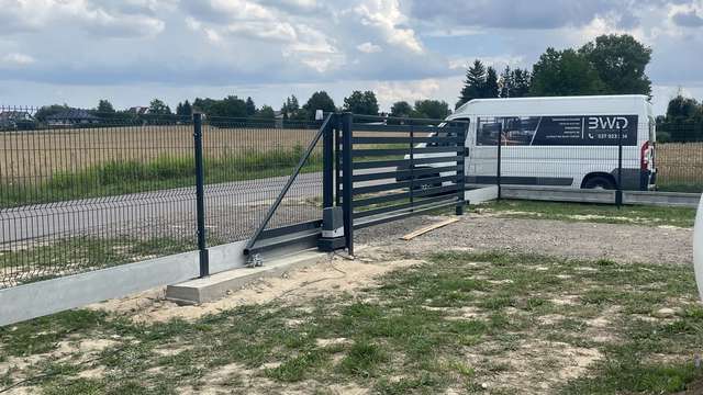 Automatyczna brama przesuwna z siatką stalową na betonowej podmurówce