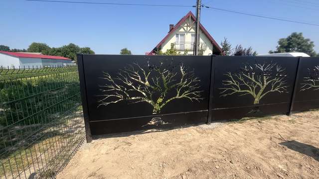 Brama wjazdowa z ażurowym wzorem drzew wyciętym w stalowych panelach