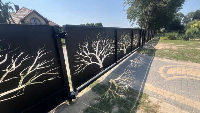 Wjazd na posesję z czarną bramą i furtką ozdobioną motywem drzew CNC