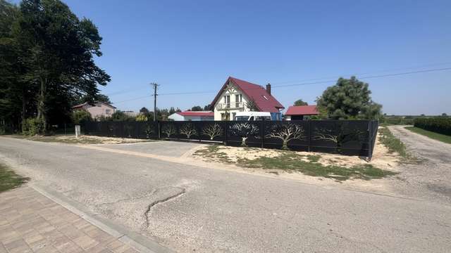 Szeroki widok czarnego ogrodzenia CNC z krajobrazem drzew od strony ulicy