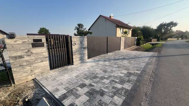 Wjazd z aluminiową bramą grzebieniową i kamiennymi słupami