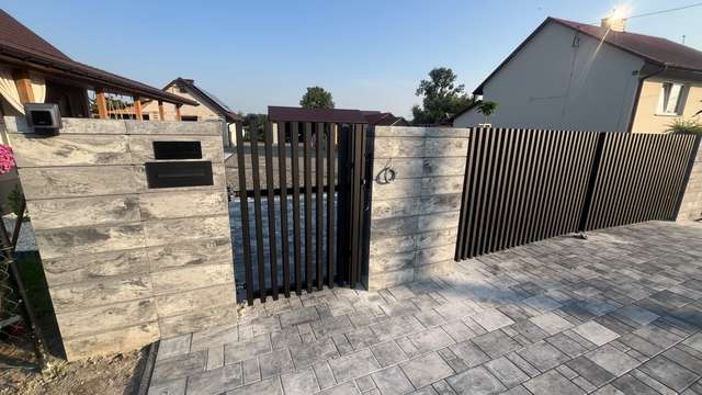 Furtka palisadowa z pionowym wypełnieniem obok aluminiowej bramy